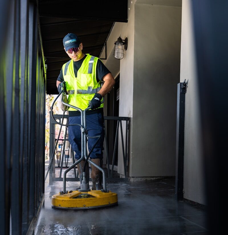 a man in a yellow vest is cleaning the floor
